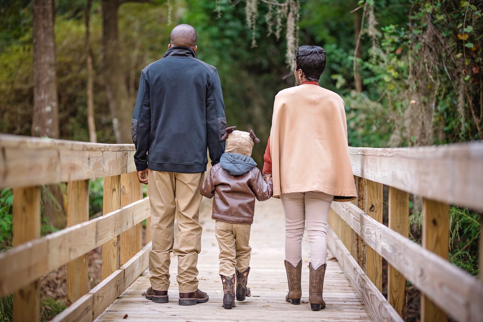 Family walking hand in hand across a wooden bridge at Dorothy B. Oven Park