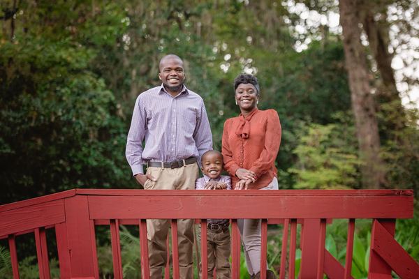 Couple smiling behind the red railing of a footbridge at Dorothy B. Oven Park