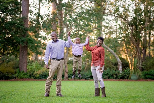 Parents lifting their little boy between them on the lawn at Dorothy B. Oven Park