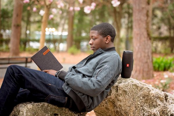 Teen reclining on a boulder with a book under the trees at Dorothy B. Oven Park