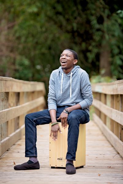 Laughing teen seated on a wooden box in the middle of a footbridge at Dorothy B. Oven Park