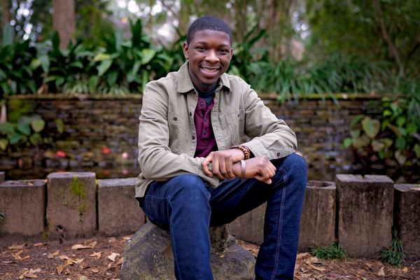 Smiling teen seated in front of a stone garden wall at Dorothy B. Oven Park