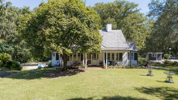 Goodwood's white historic house behind a large shade tree across a sunny lawn