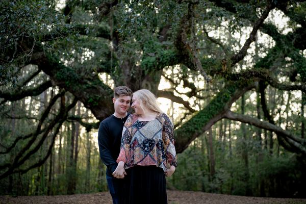 Engaged couple embracing in front of the Lichgate live oak