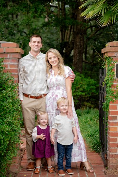 Family of four standing at a brick garden gateway framed by greenery at Maclay Gardens in Tallahassee
