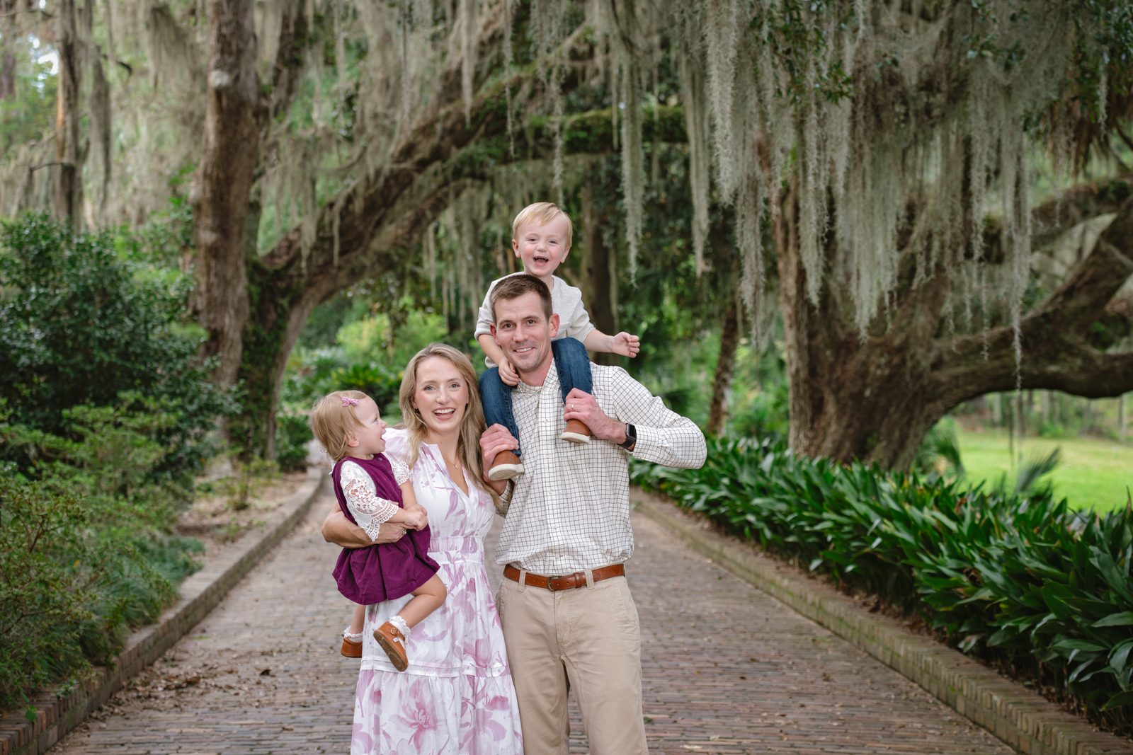 Family of four on a brick garden path beneath moss-draped live oaks at Maclay Gardens, Tallahassee