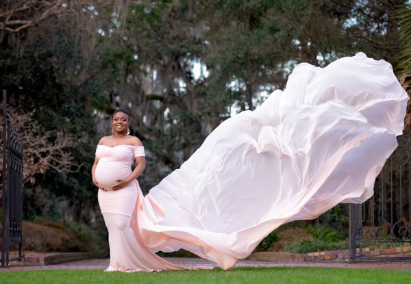 Expectant mother with a long sheer train blowing in the breeze in the gardens at Maclay Gardens, Tallahassee