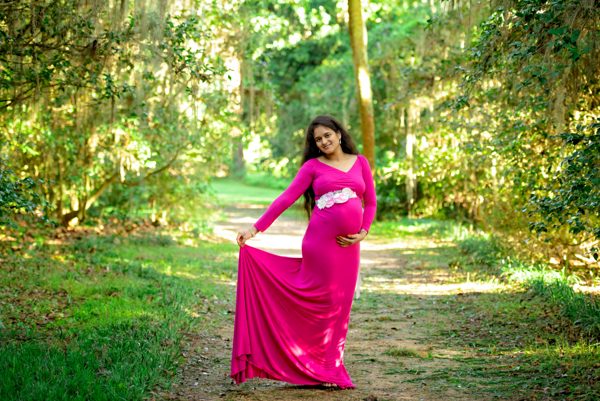 Maternity portrait in a magenta gown on a shaded garden path at Maclay Gardens, Tallahassee