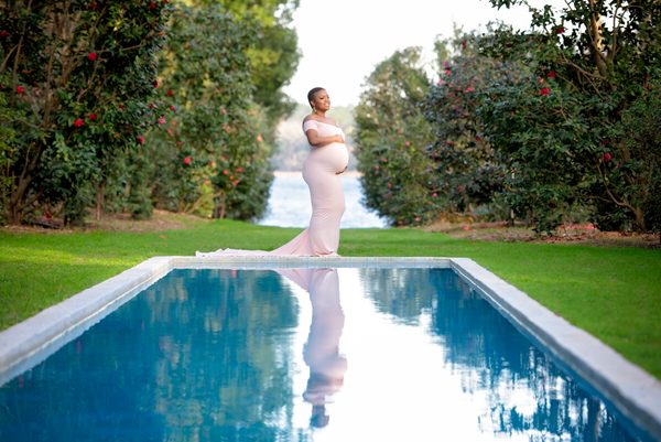 Expectant mother in a flowing white gown reflected in the long pool at Maclay Gardens, Tallahassee