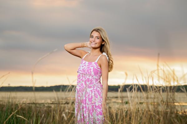 Young woman in a floral sundress among tall lakeside grasses at sunset, Millers Landing