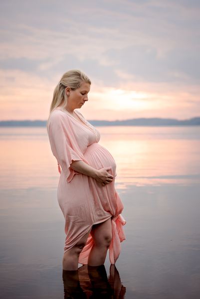 Expectant mother standing in the lake at sunset for a maternity portrait at Millers Landing
