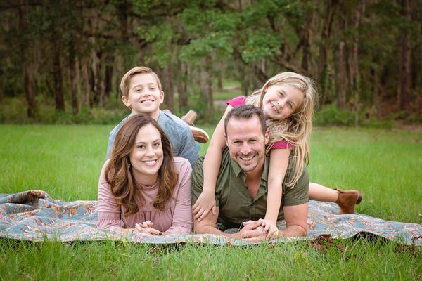 Family lying on a blanket in the grass beneath the trees at Millers Landing