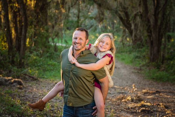 Father giving his daughter a piggyback ride on a forest trail at Millers Landing