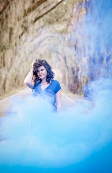 Woman in a blue dress surrounded by blue smoke on the oak canopy road at Millers Landing