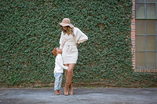 Mother in a cream sweater and hat with her young son before an ivy-covered wall at Pebble Hill Plantation