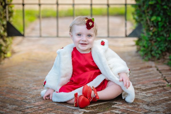 Toddler in a red dress and white jacket sitting on a brick path at Pebble Hill Plantation near Tallahassee