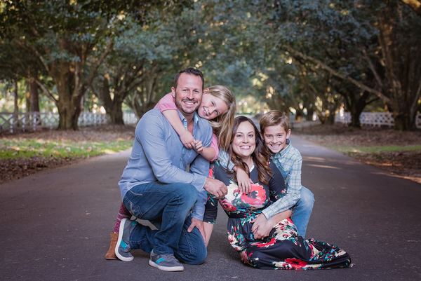 Family sitting close together on the oak-lined drive at Rose Hill