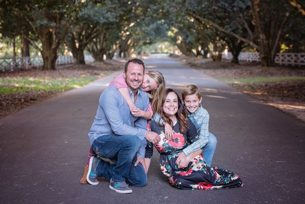 Smiling family huddled together on the drive under the oaks at Rose Hill