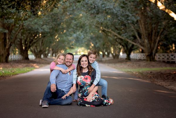 Family cuddled together seated on the avenue beneath arching oaks at Rose Hill