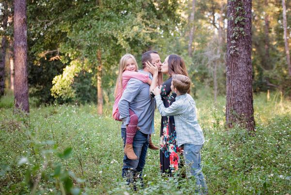 Family embracing among tall trees and green brush at Rose Hill