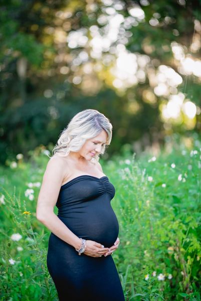 Expectant mother in a black gown among tall grass and wildflowers at the Alford Greenway