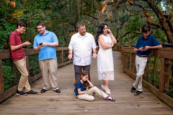 Extended family gathered on a wooden bridge in the trees at Tom Brown Park