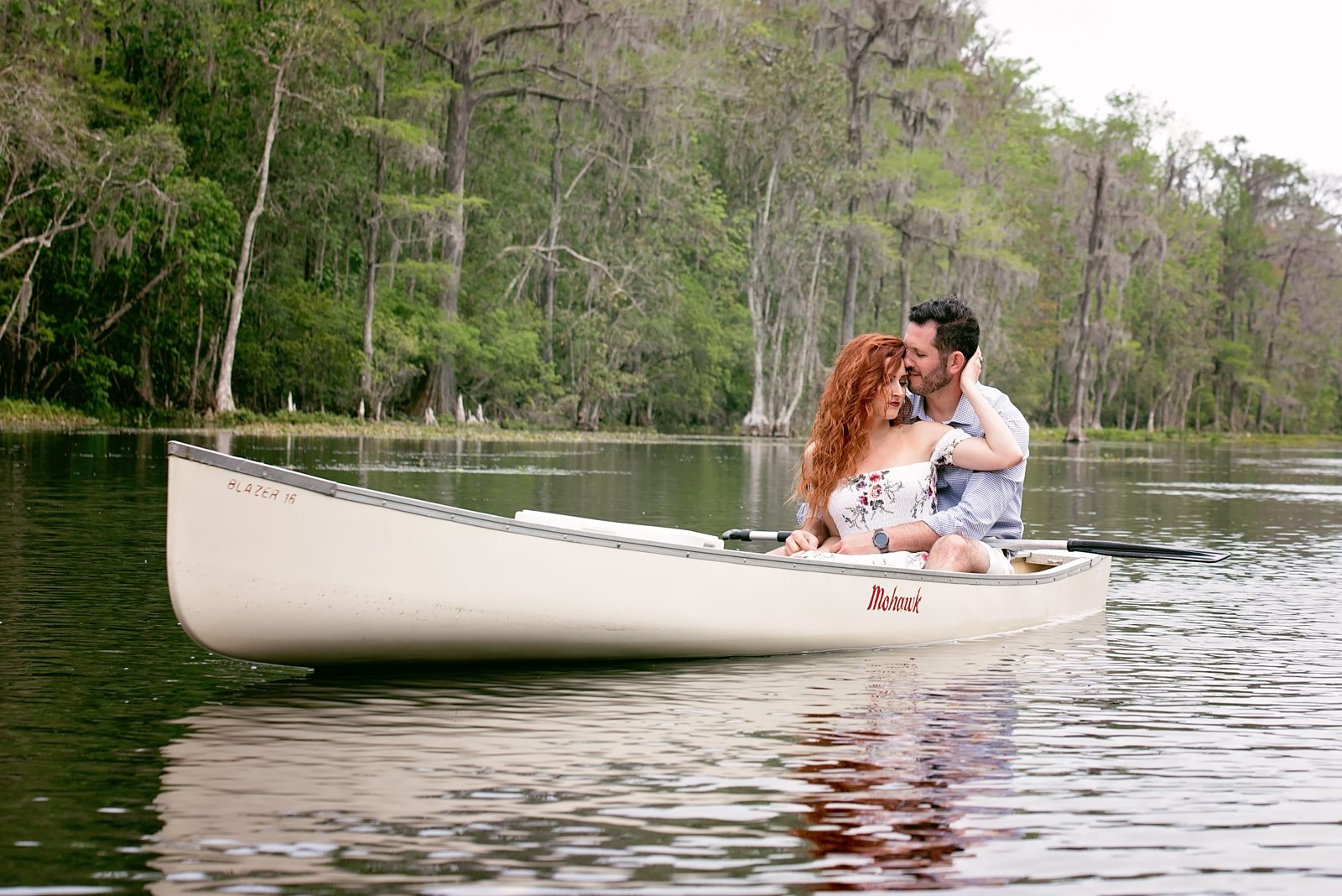 Couple embracing in a white canoe on the Wacissa River near Tallahassee, with cypress trees along the bank