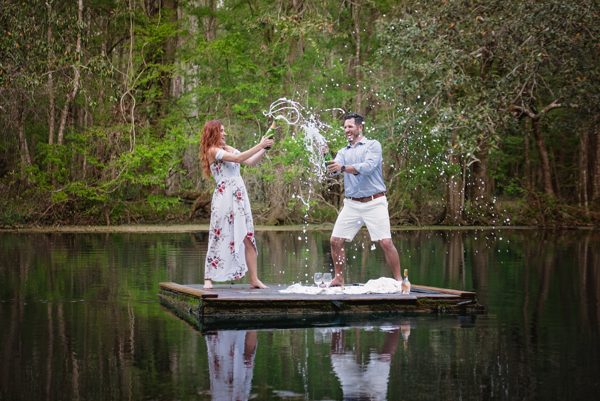 Couple splashing water on a floating wooden dock on the dark, still Wacissa River near Tallahassee