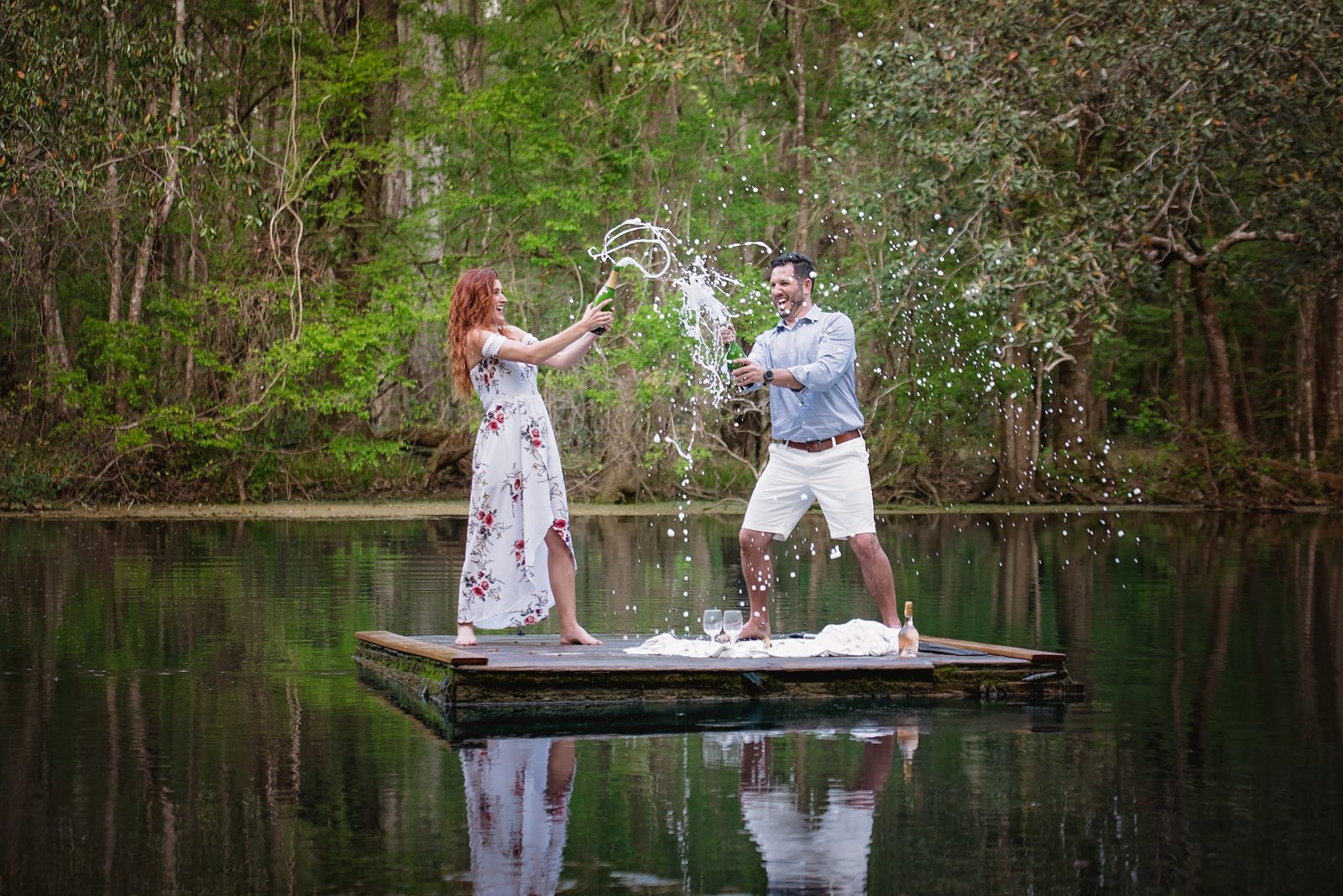 Couple splashing water on a floating wooden dock on the dark, still Wacissa River near Tallahassee